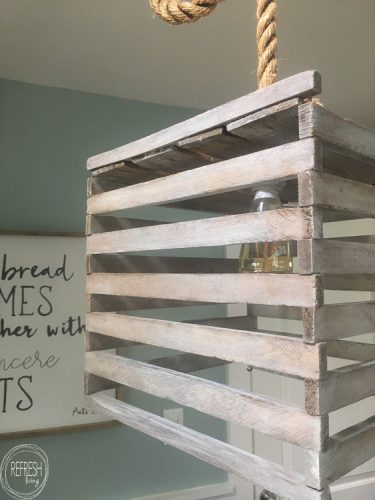 Farmhouse style light fixture made from an antique egg crate. It's easy to make using a pendant light kit and a simple white technique.