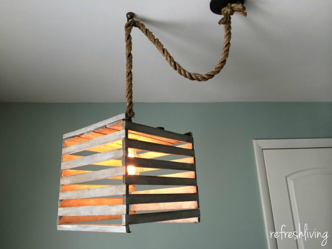 Farmhouse style light fixture made from an antique egg crate. It's easy to make using a pendant light kit and a simple white technique.