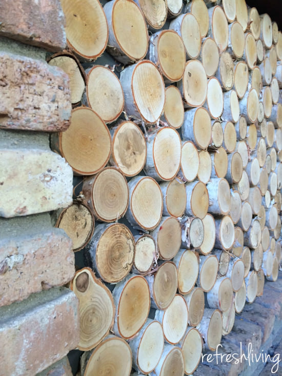 DIY fireplace screen with wood discs to look like stacked logs.
