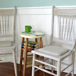 Refinished farmhouse chairs with a whitewash finish and mattress ticking seat