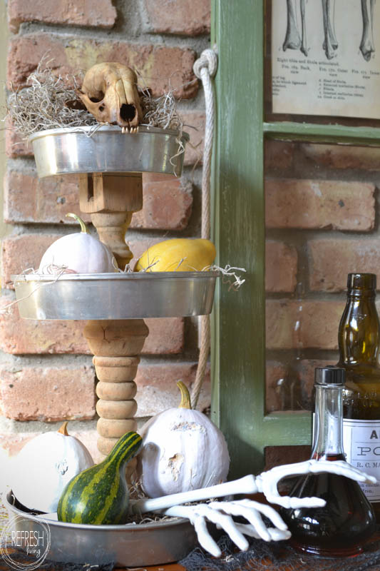 DIY halloween mantel with tiered tray holding pumpkins and skulls