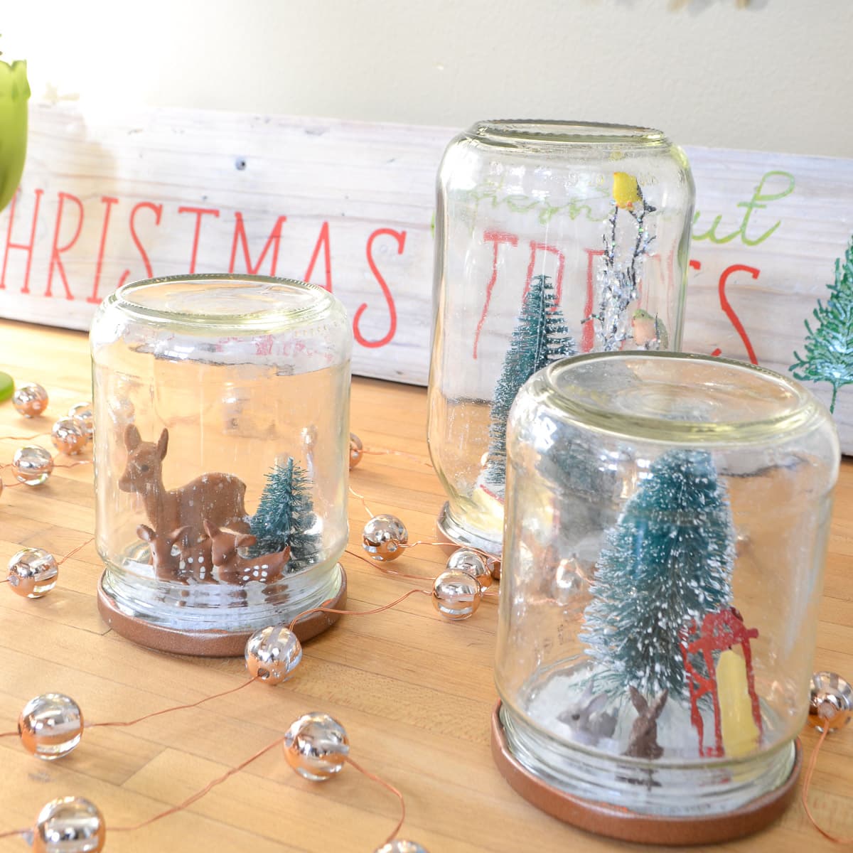reuse glass jars as DIY snow globes for easy kids craft for Christmas with little deer, bottle brush tree and woodland animals