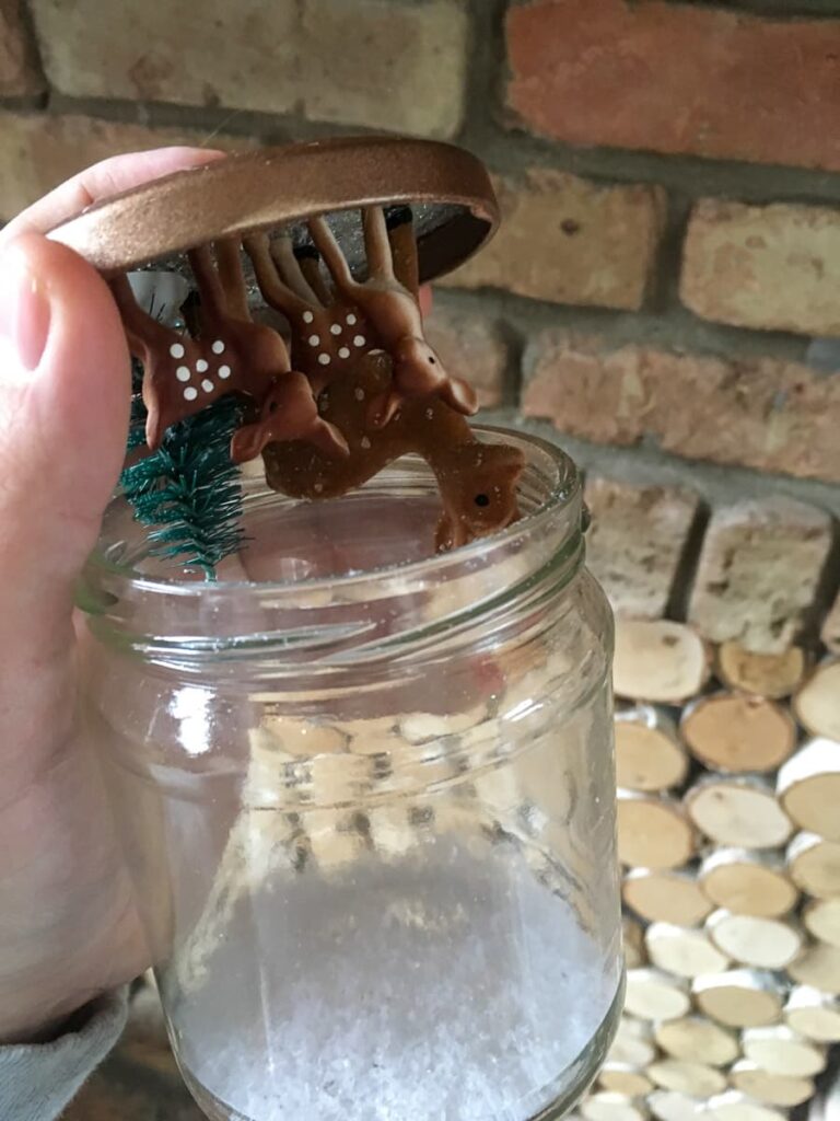 DIY Christmas snow globes using glass food jars with small deer and bottle brush tree