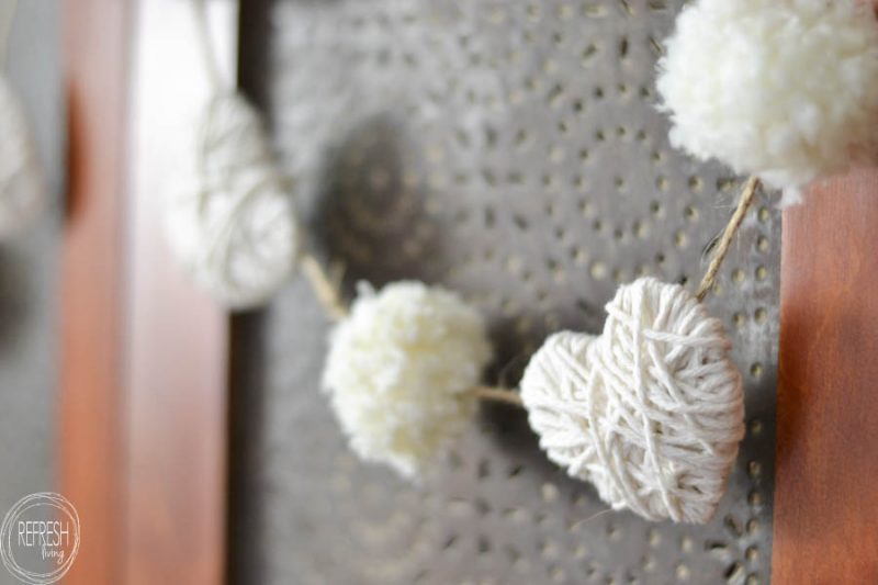 valentines garland with yarn hearts and yarn pom poms in white for neutral valentines decor