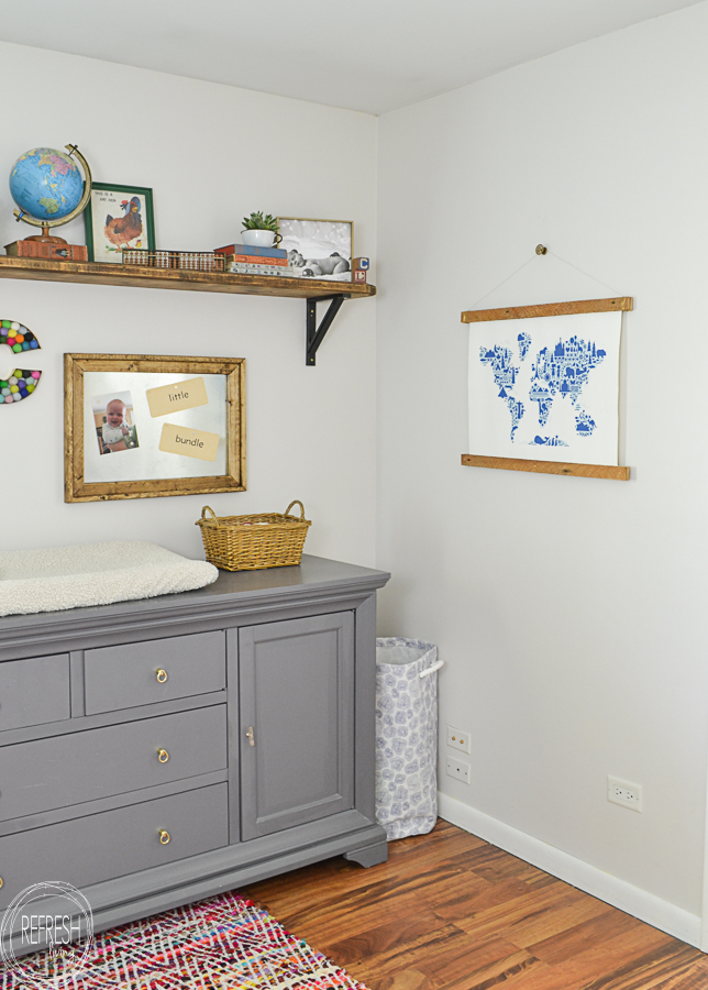 nursery with gray dresser, wood shelf, vintage toys and games, and a wall hanging map