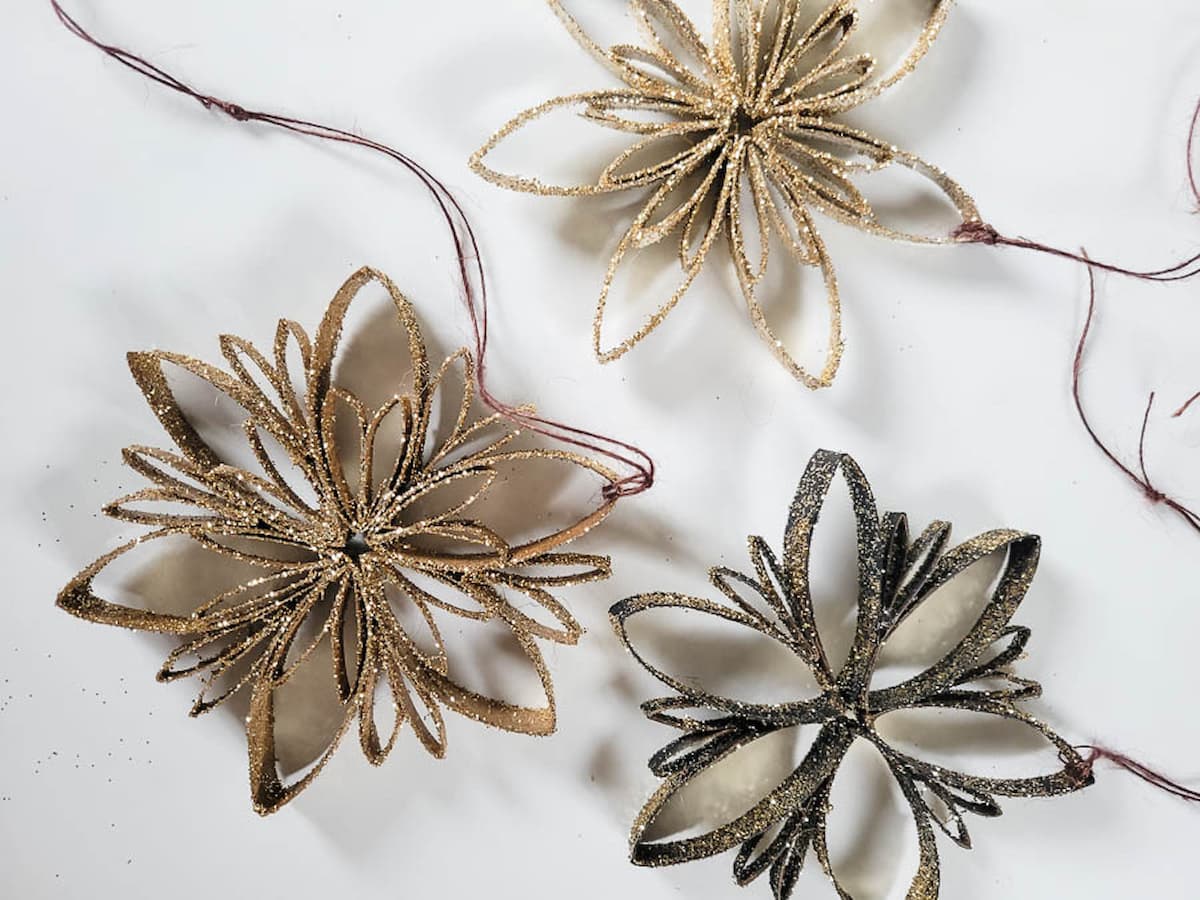 make snowflake ornaments with gold glitter and toilet paper roll