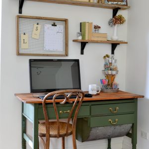 An antique baker's table becomes a desk by removing one of the flour drawers. Vintage modern office with open shelves and farmhouse boho vintage feel. Dark green desk with natural wood top desk via Refresh Living.