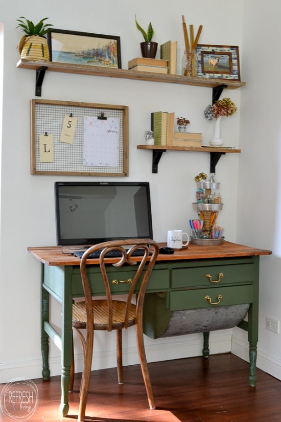 An antique baker's table becomes a desk by removing one of the flour drawers. Vintage modern office with open shelves and farmhouse boho vintage feel. Dark green desk with natural wood top desk via Refresh Living.