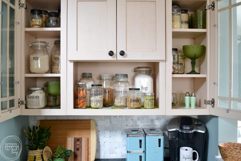 open pantry on kitchen shelves organized with glass jars for dried goods