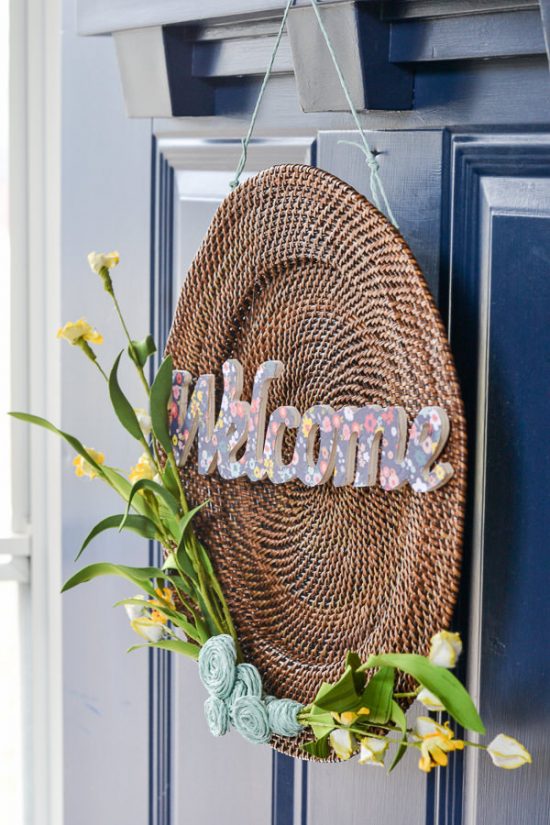 This is a plate charger - I see these at the thrift store all the time. Now, I'll definitely be picking one up to make a wreath like this one. DIY spring wreath with wood, twine, yellow flowers and welcome cut out.