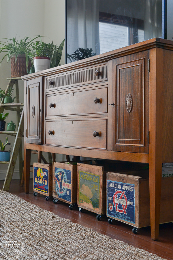 vintage sideboard as a tv stand and using vintage crates with wheels for toy storage in the living room