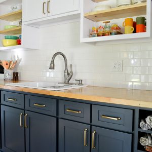 kitchen with refaced cabinet doors painted in white upper and blue lower cabinets and butcher block top