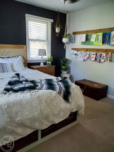 Check out this master bedroom makeover completed with refinished furniture, a DIY modern headboard, a painted black feature wall, vintage fabric and a kids art display.