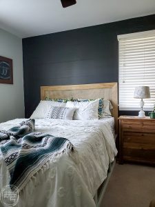 Check out this master bedroom makeover completed with refinished furniture, a DIY modern headboard, a painted black feature wall, vintage fabric and a kids art display.
