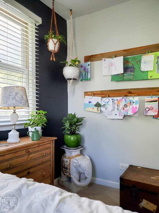 Check out this master bedroom makeover completed with refinished furniture, a DIY modern headboard, a painted black feature wall, vintage fabric and a kids art display.