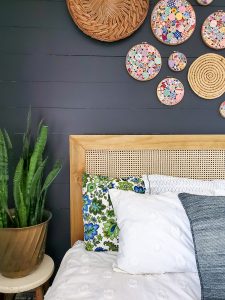 black shiplap wall in a bedroom with DIY cane headboard and vintage yo yo quilt embroidery hoop art