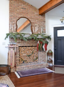 Mix of greenery, brass candlesticks, and vintage decor in this Christmas mantel
