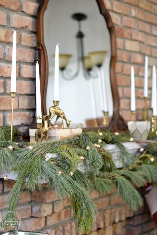 Mix of greenery, brass candlesticks, and vintage decor in this Christmas mantel