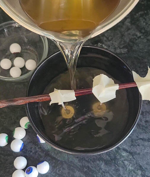 pour melted wax into a bowl and add eyeballs for Halloween DIY candles