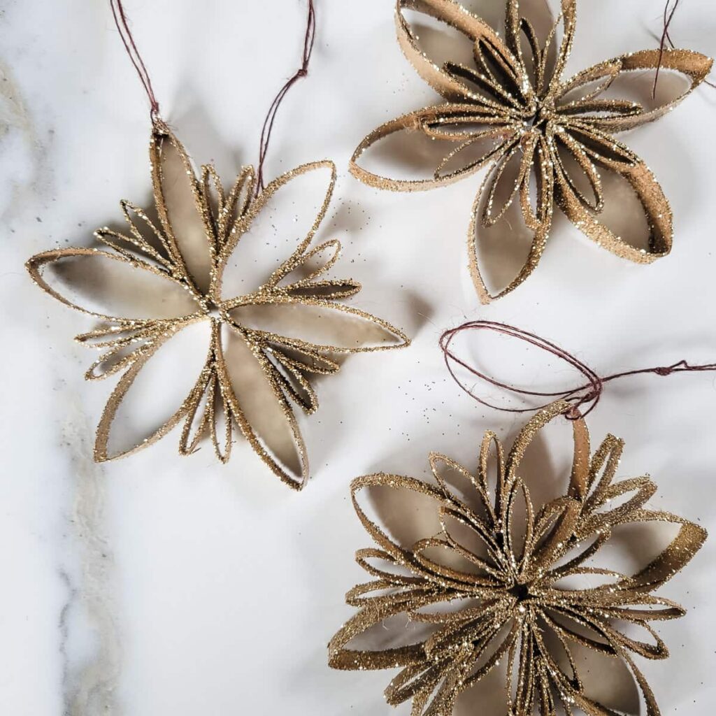 make snowflake ornaments with gold glitter and toilet paper roll snowflake designs